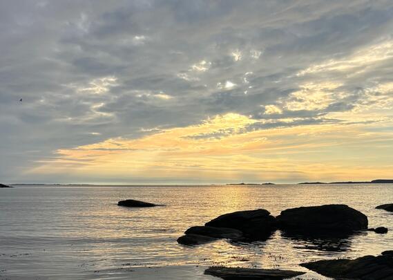 Strand, himmel og sol gjennom sky