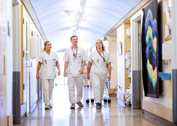Tre sykepleiere i sykehuskorridor
