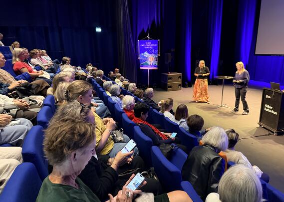 Bilde av salen med deltager og Tiril og Marthe på scenen