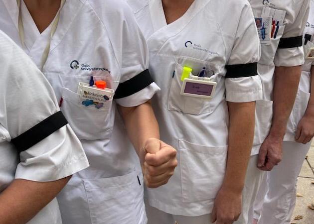 Bildet viser sykepleiere i uniform med sorte sørgebånd.