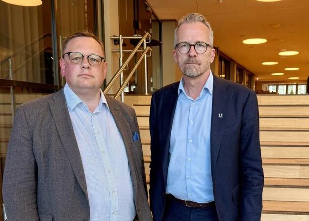 To menn med briller og dress står ved siden av hverandre
