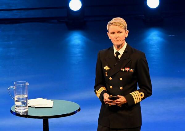 En kvinne i uniform fra Forsvarets sanitet snakker på en scene.