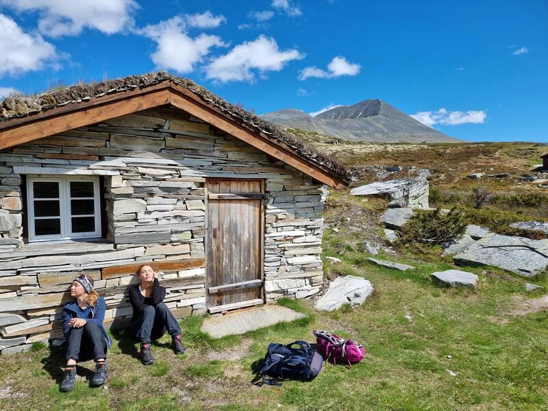 hytte med to personer sittende i naturen