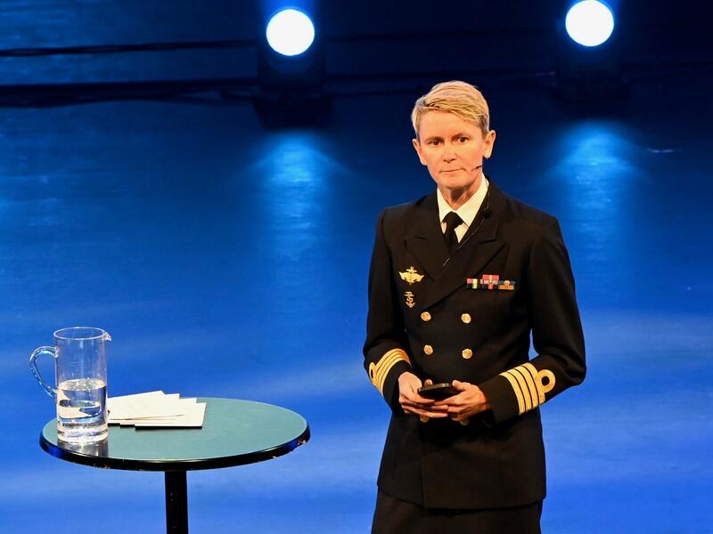 En kvinne i uniform fra Forsvarets sanitet snakker på en scene.