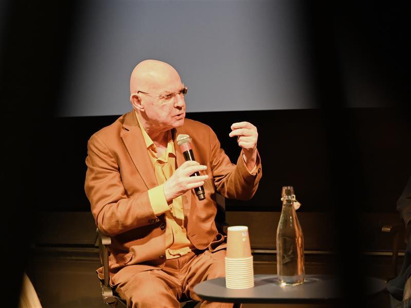 Mann snakker i mikron og gestikulerer.