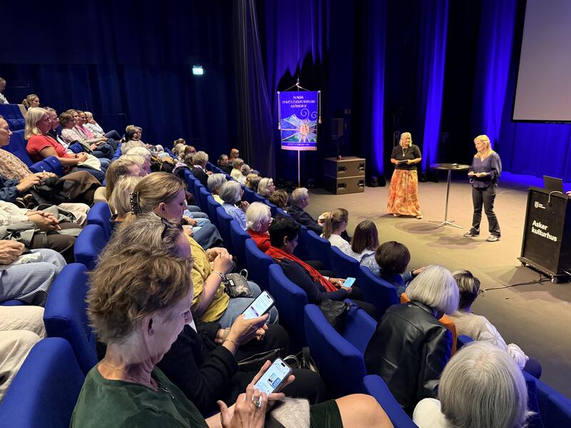 Bilde av salen med deltager og Tiril og Marthe på scenen