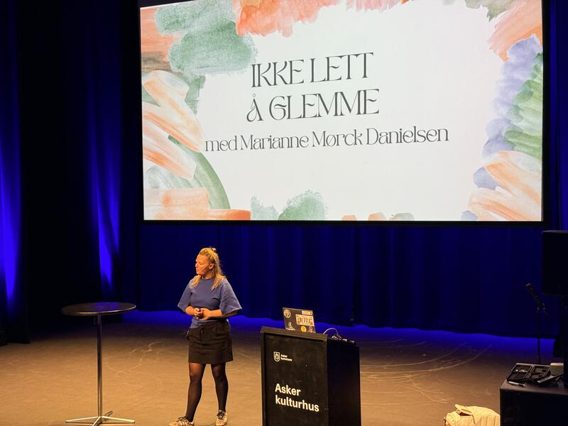 Marianne Danielsen på scenen med "ikke lett å glemme" lysbide i bakgrunnen